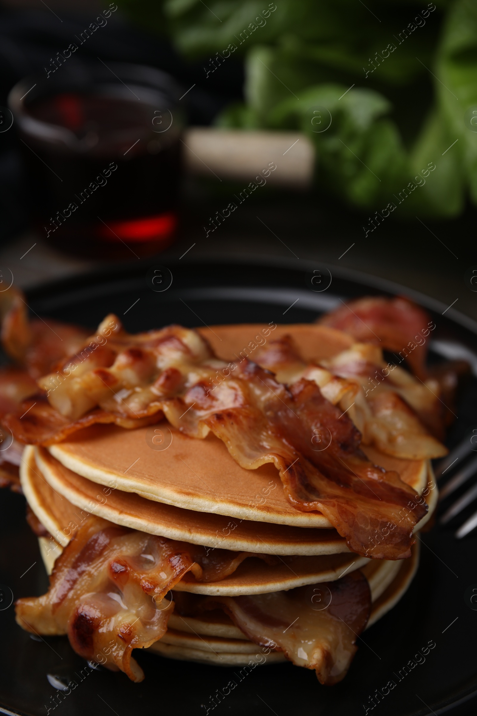 Photo of Delicious pancakes with fried bacon served on wooden table, closeup