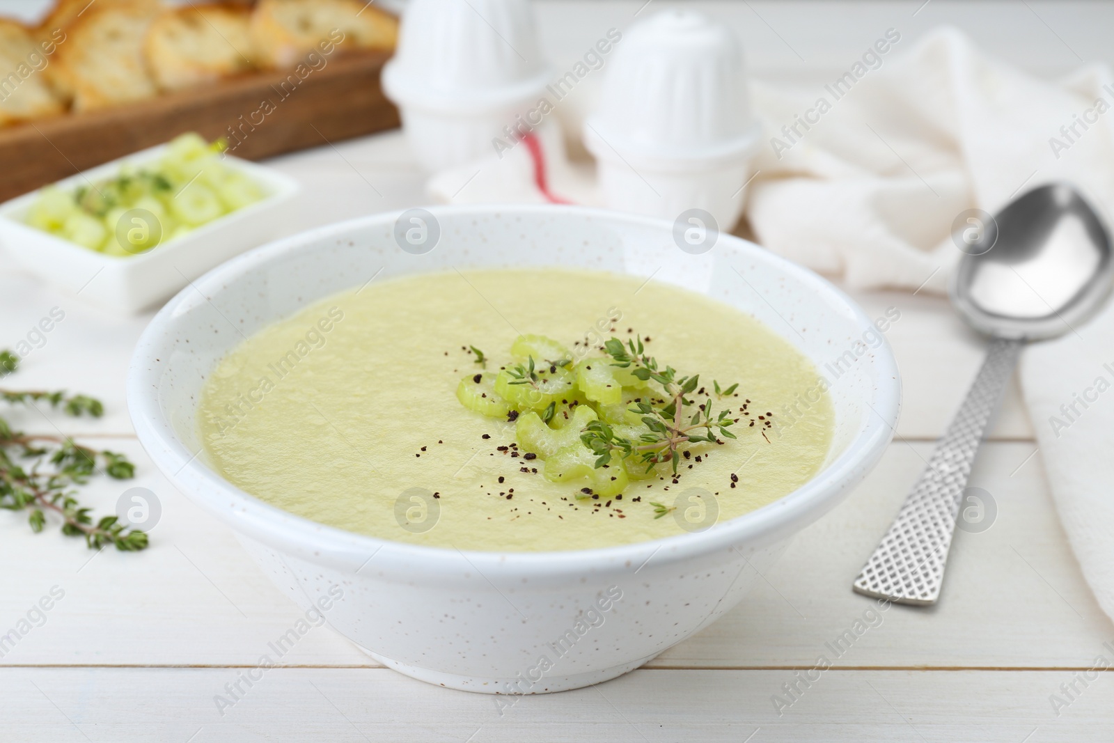 Photo of Bowl of delicious celery soup on white wooden table, closeup