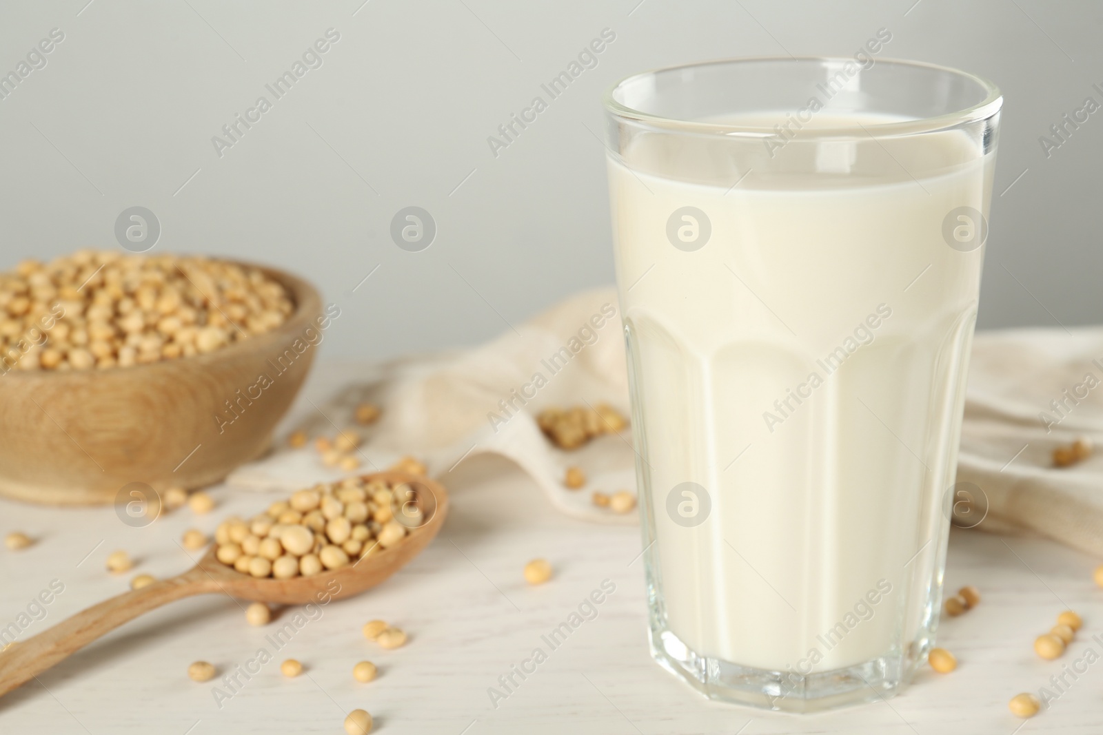Photo of Glass with fresh soy milk and grains on white wooden table, closeup