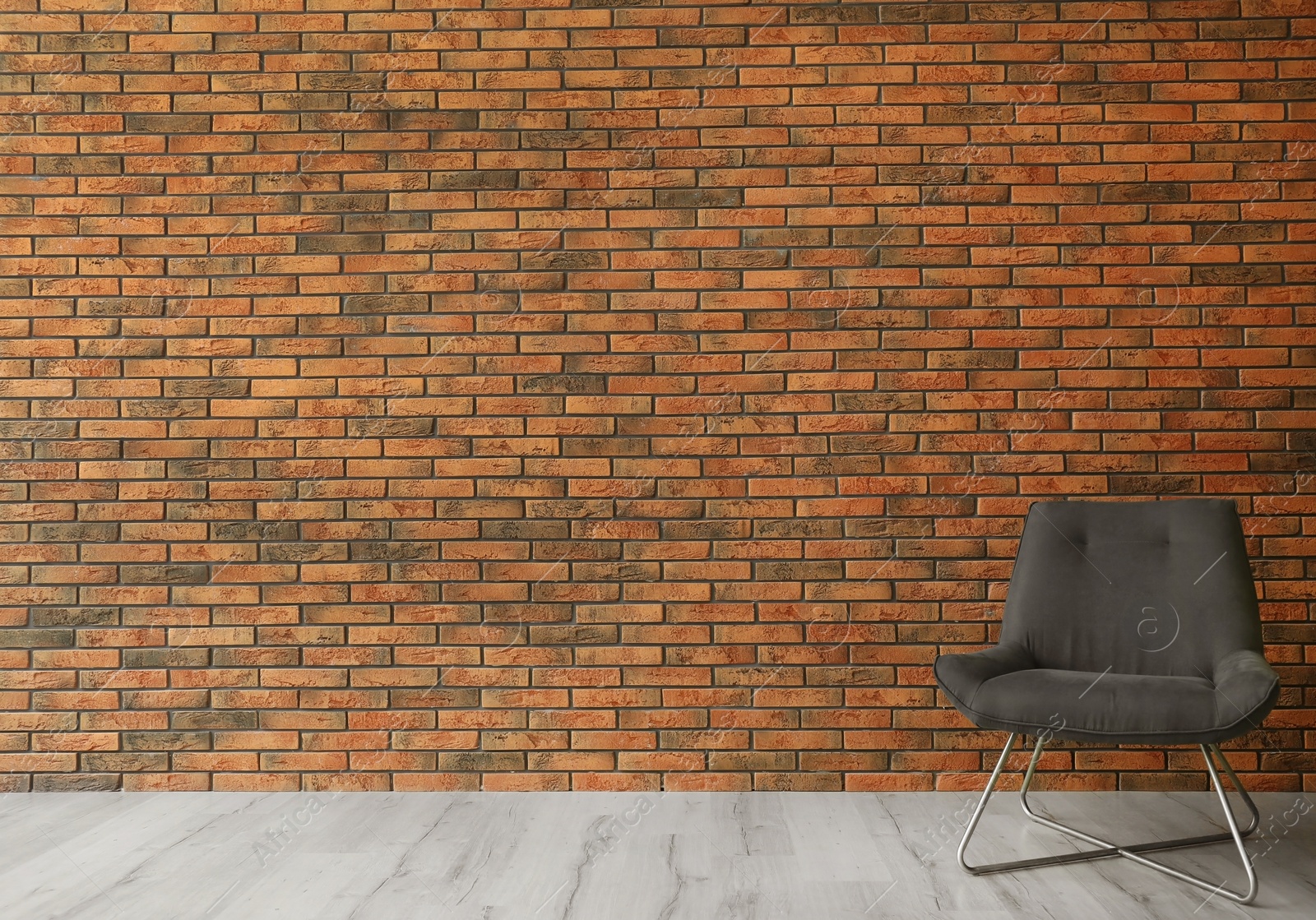 Photo of Grey modern chair and lamp near brick wall. Modern room interior