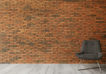 Grey modern chair and lamp near brick wall. Modern room interior