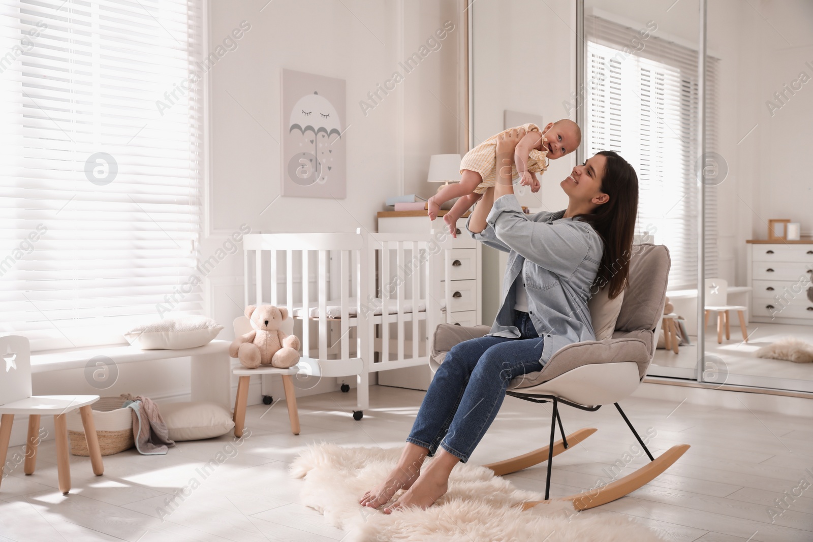 Photo of Happy young mother with her cute baby in rocking chair at home