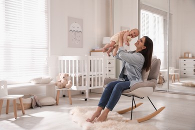 Photo of Happy young mother with her cute baby in rocking chair at home