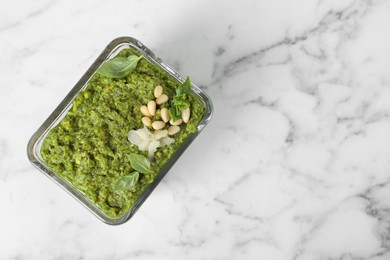 Photo of Delicious pesto sauce in bowl on white marble table, top view. Space for text