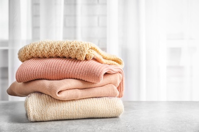 Photo of Stack of warm knitted clothes on table