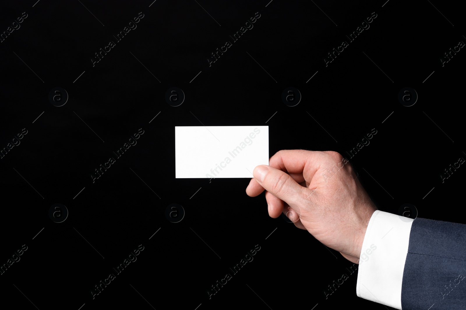 Photo of Businessman holding blank business card on black background, closeup. Space for text