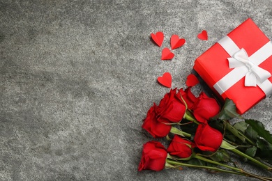 Photo of Beautiful red roses, gift box and paper hearts on grey background, flat lay with space for text. Valentine's Day celebration