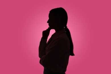 Photo of Silhouette of anonymous woman on pink background