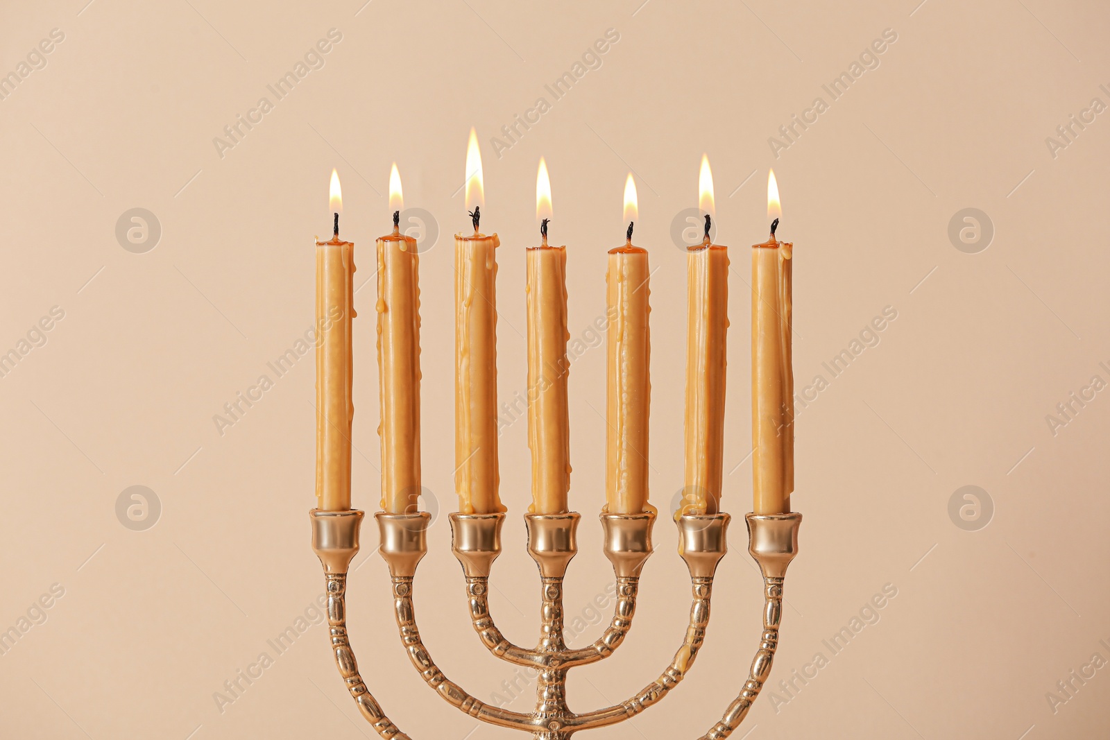 Photo of Golden menorah with burning candles on beige background