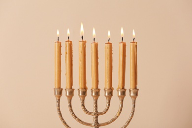 Photo of Golden menorah with burning candles on beige background