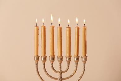 Golden menorah with burning candles on beige background