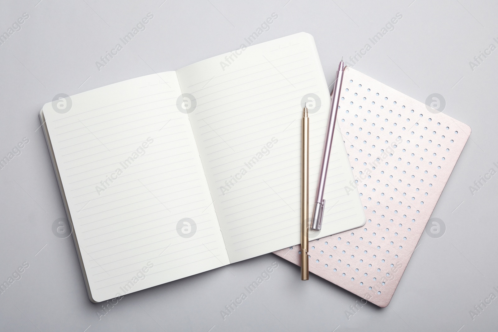 Photo of Stylish notebooks and pens on grey background, top view