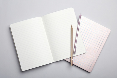 Photo of Stylish notebooks and pens on grey background, top view