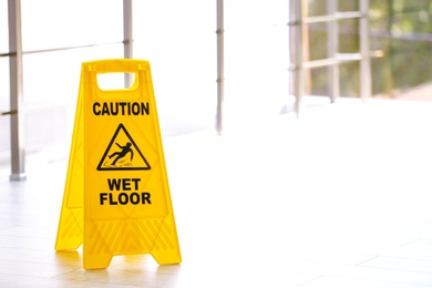 Photo of Safety sign with phrase Caution wet floor, indoors. Cleaning service