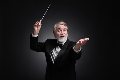 Professional conductor with baton on black background