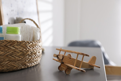 Photo of Wicker basket with accessories and wooden airplane on grey table in child room
