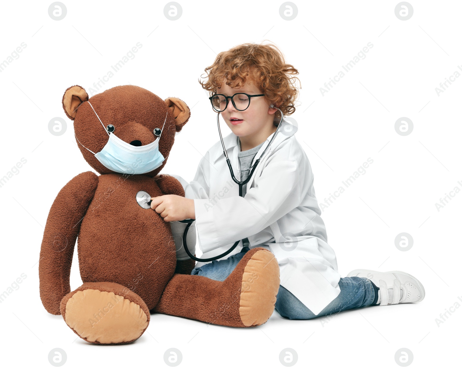Photo of Little boy playing doctor with toy bear on white background