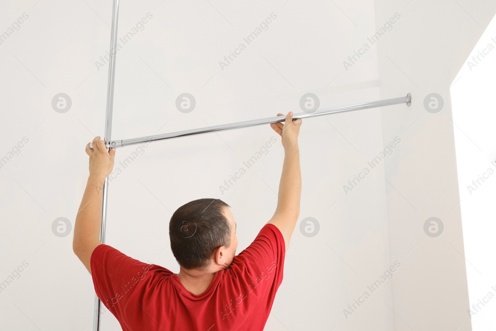 Photo of Worker installing new metal pipes indoors, back view