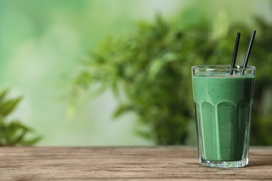 Glass of spirulina smoothie on table against blurred background. Space for text