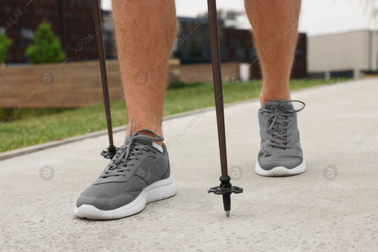 Photo of Man practicing Nordic walking with poles outdoors, closeup