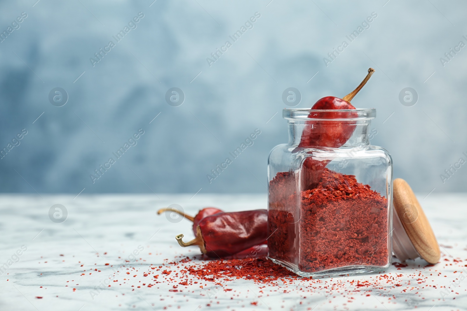 Photo of Jar with crushed chili pepper and pods on table