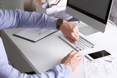 Young man checking time on his wristwatch at workplace