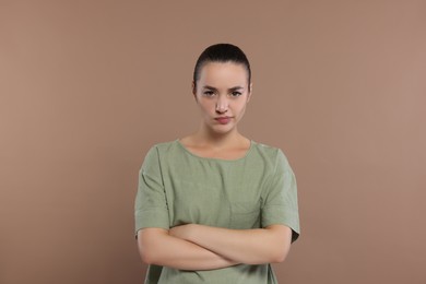 Photo of Portrait of resentful woman with crossed arms on brown background