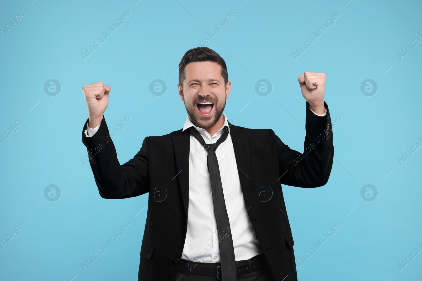 Photo of Emotional sports fan celebrating on light blue background