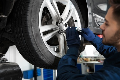 Technician working with car in automobile repair shop