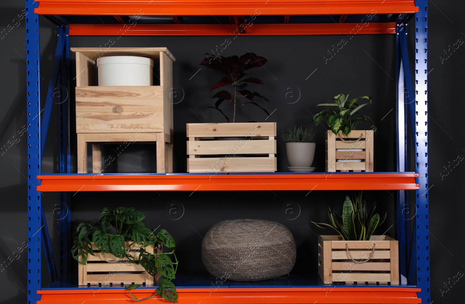 Photo of Metal shelving unit with wooden crates and different household stuff on black background