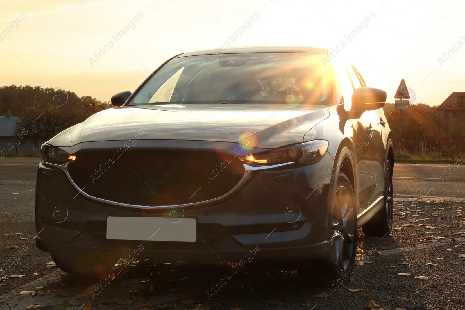 Photo of Black modern car parked on road at sunset