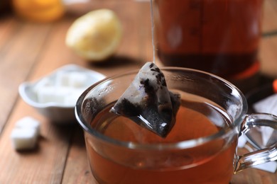 Photo of Taking tea bag out of glass cup on table, closeup