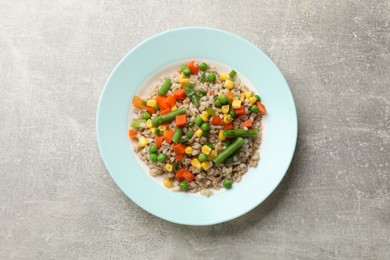 Tasty pearl barley porridge with vegetables on light textured table, top view