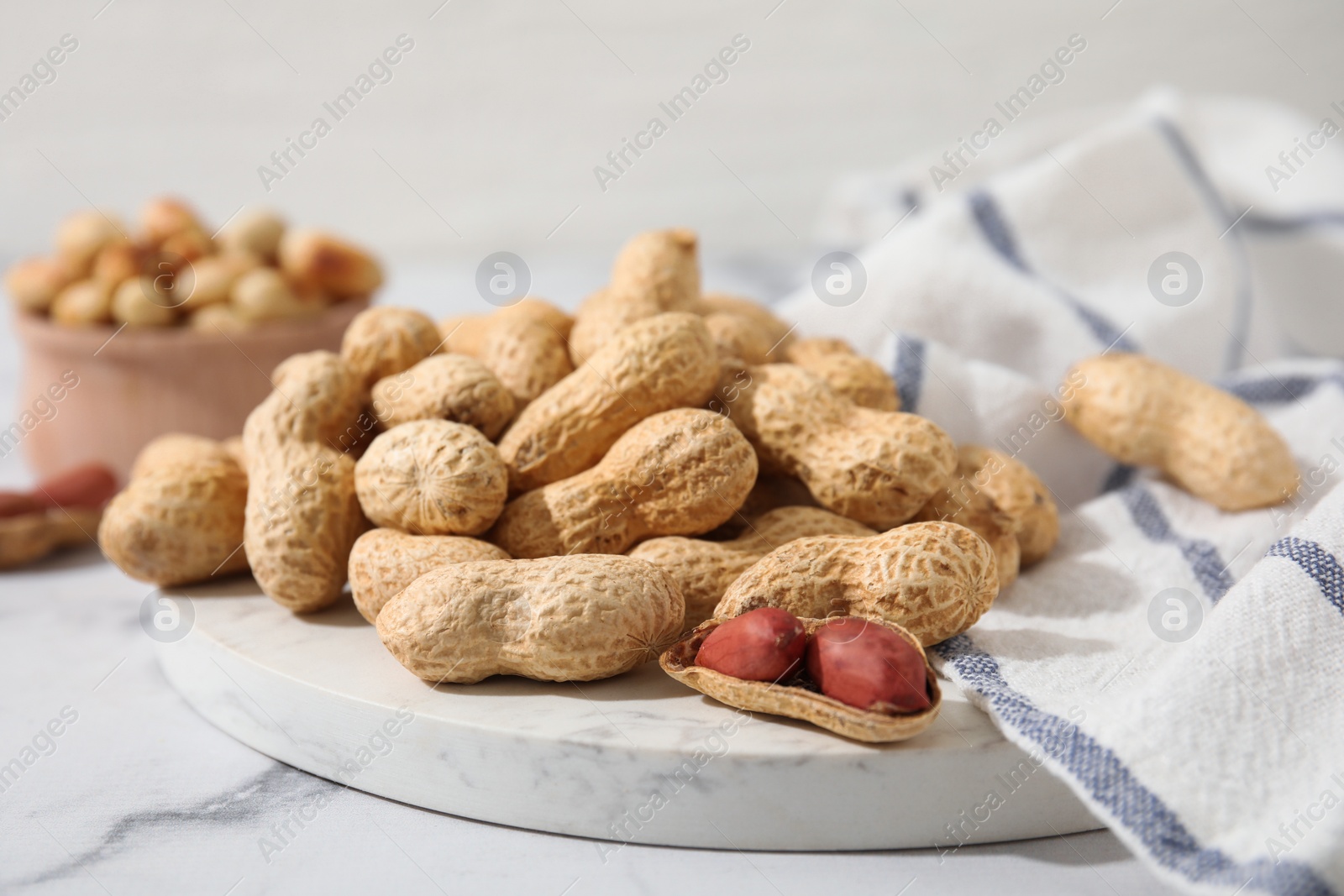 Photo of Fresh unpeeled peanuts on white marble table, closeup