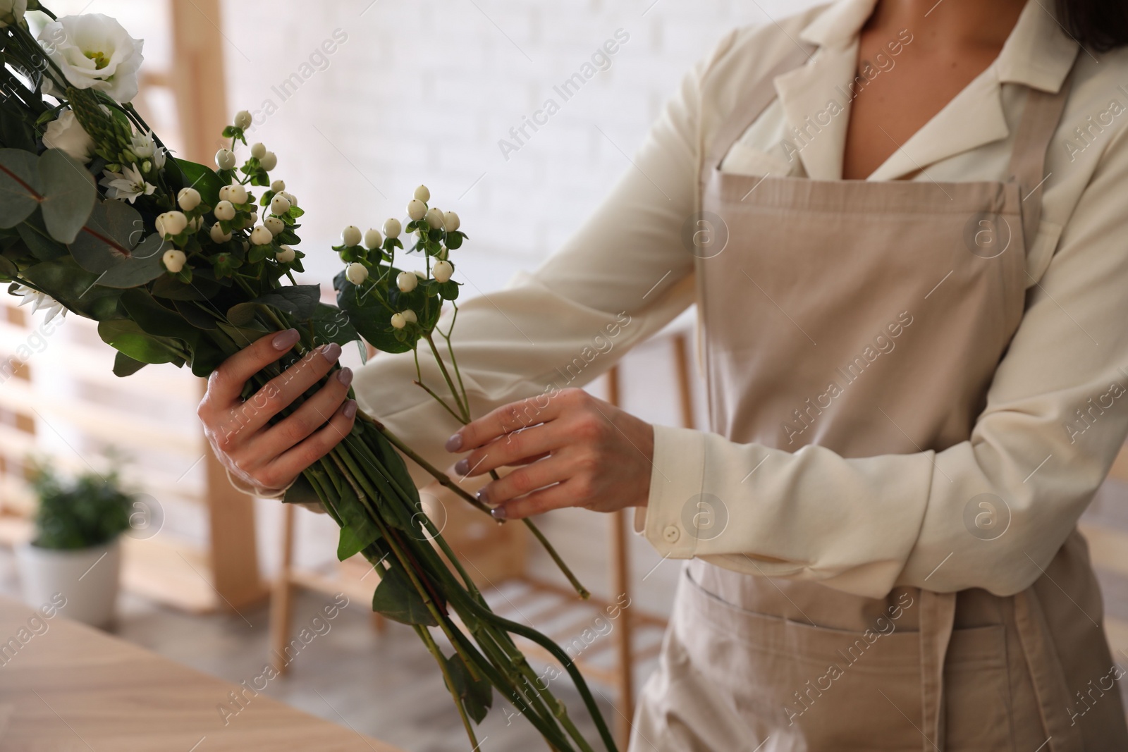 Photo of Florist making beautiful bouquet at table in workshop, closeup