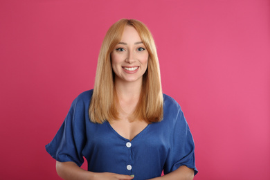 Photo of Beautiful young woman with blonde hair on pink background