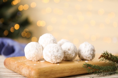 Photo of Christmas snowball cookies on light table against blurred lights, closeup