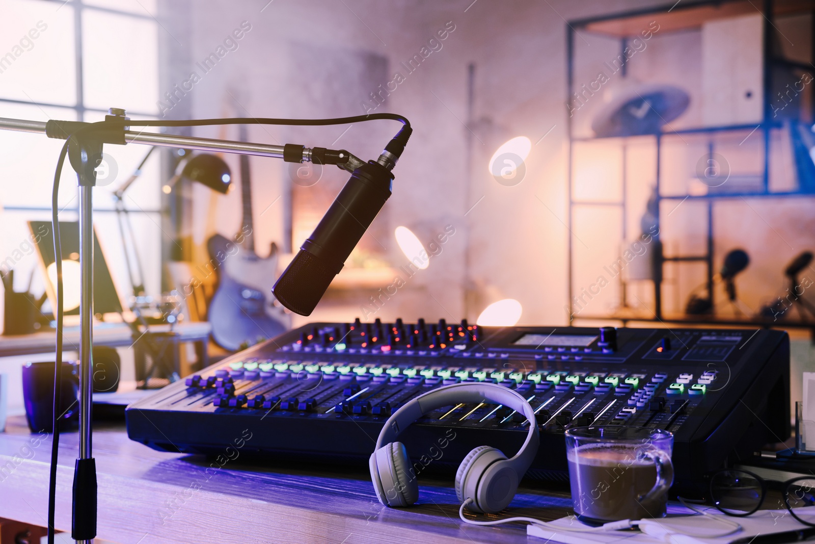 Photo of Microphone near table with professional mixing console in radio studio