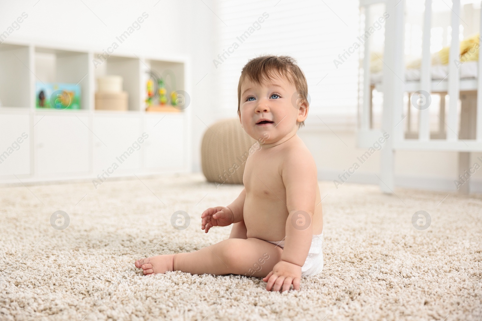 Photo of Cute baby boy sitting on carpet at home