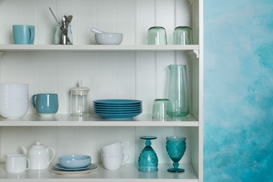 Photo of White shelving unit with set of dishware near color wall