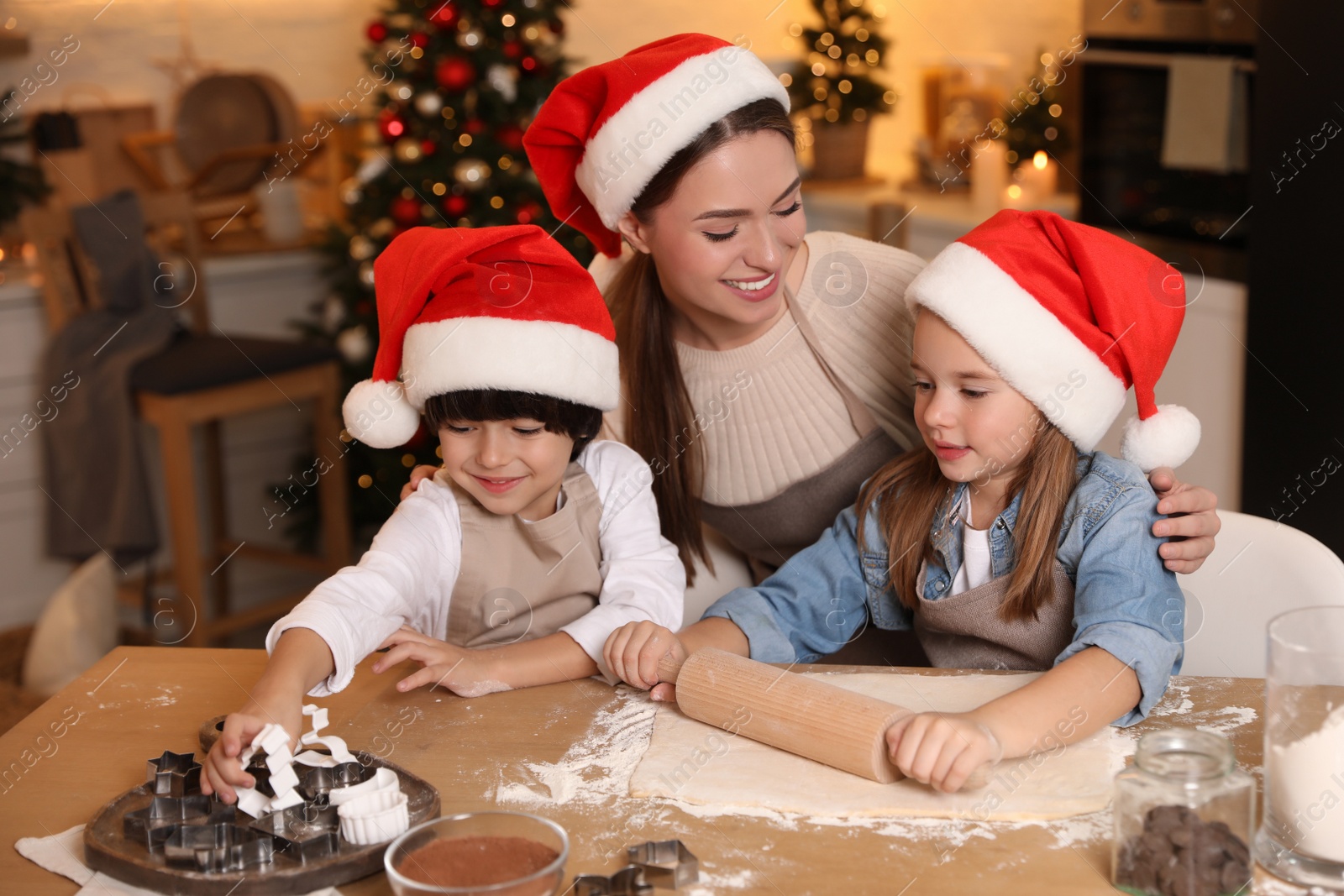 Photo of Mother with her cute little children making dough for Christmas cookies in kitchen