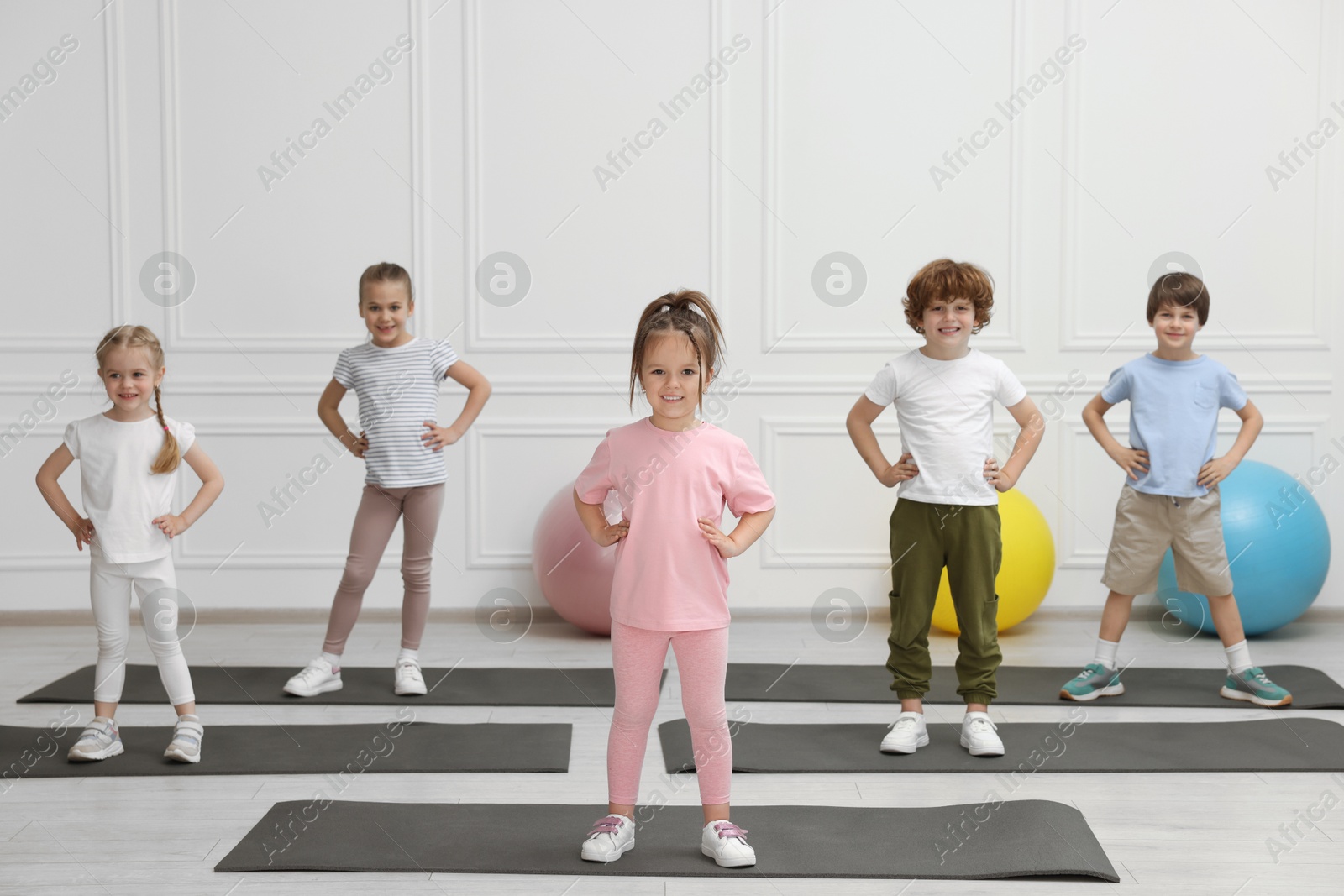 Photo of Group of children doing gymnastic exercises on mats indoors