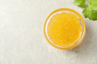 Photo of Fresh pike caviar in bowl and parsley on light grey table, top view. Space for text