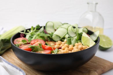 Photo of Tasty salad with chickpeas, cherry tomatoes and cucumbers on wooden board, closeup