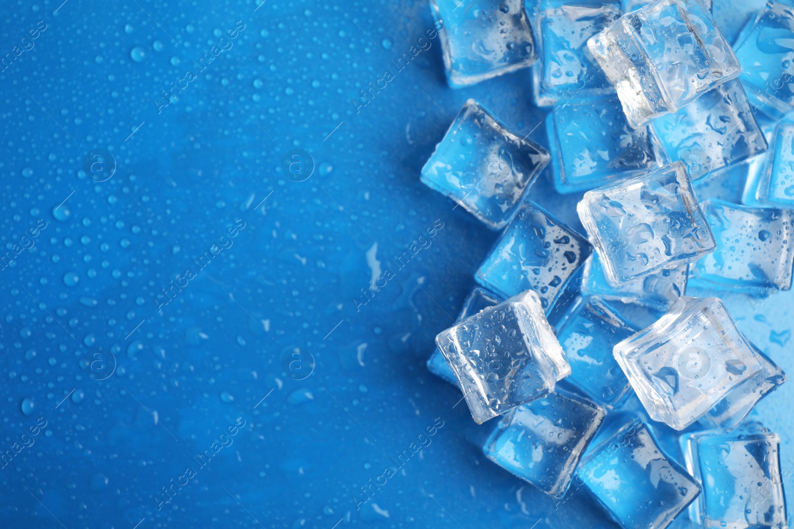 Photo of Ice cubes with water drops on light blue background, flat lay. Space for text