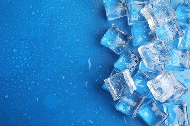 Ice cubes with water drops on light blue background, flat lay. Space for text