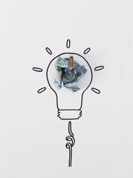 Composition with crumpled banknote and drawing of lamp bulb on white background, top view. Creative concept