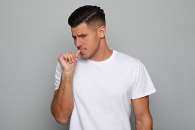 Photo of Man biting his nails on grey background, space for text. Bad habit