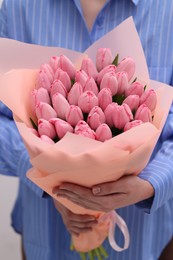 Woman holding bouquet of pink tulips indoors, closeup