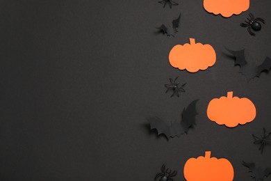 Flat lay composition with paper bats, pumpkins and spiders on black background, space for text. Halloween decor